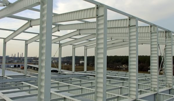 The metal frame of the warehouse building made of SIN beams is painted white. Construction of corrugated I-beams.